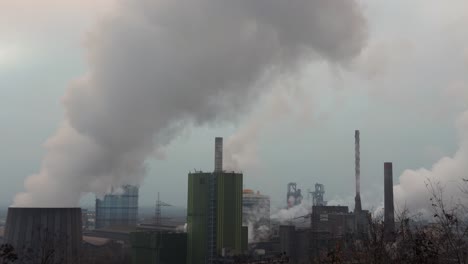 cooling towers of a factory releasing white smoke to atmosphere