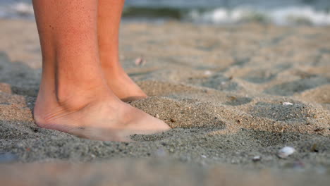 bare feet of a woman playing sand at the beach