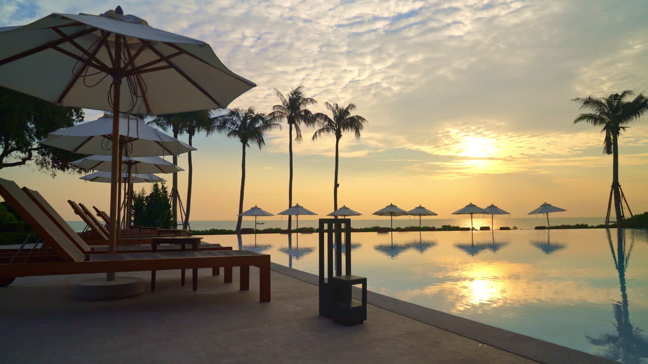 Sombrilla con piscina de cama alrededor de la piscina con fondo de mar océano al atardecer o al amanecer - concepto de vacaciones y vacaciones