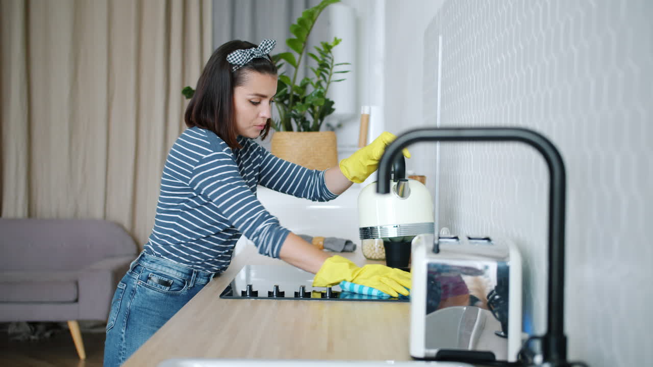 Una mujer limpiando la cocina.