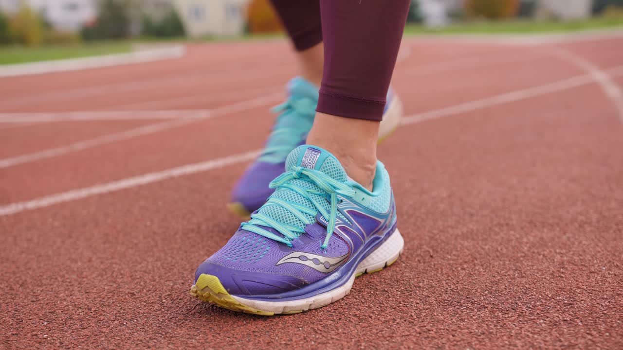 Inquadratura delle scarpe da running di un'atleta che si allunga e cambia posizione, al rallentatore.
