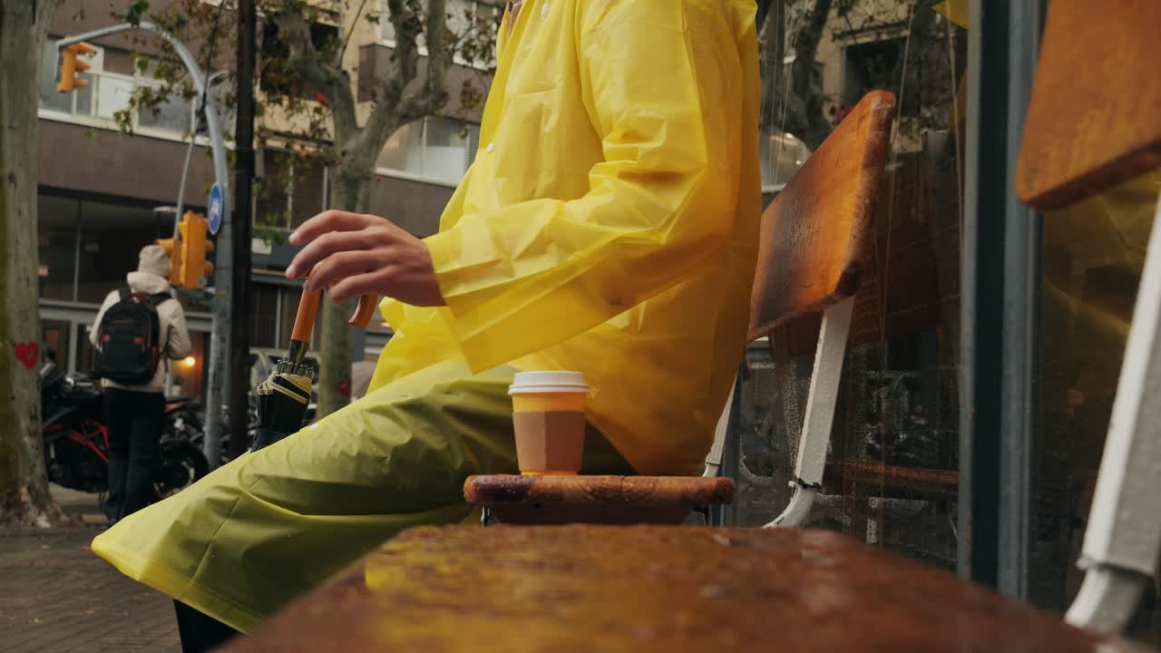 Business man tourist person with umbrella and raincoat on rainy european city street, lights reflecting, walking in Barcelona or Amsterdam during the rain