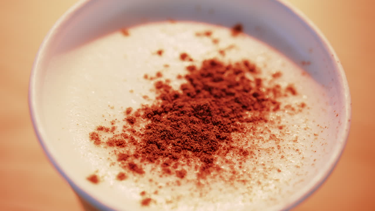 Primo piano di cacao spolverato su latte schiumoso, con toni caldi e intensi