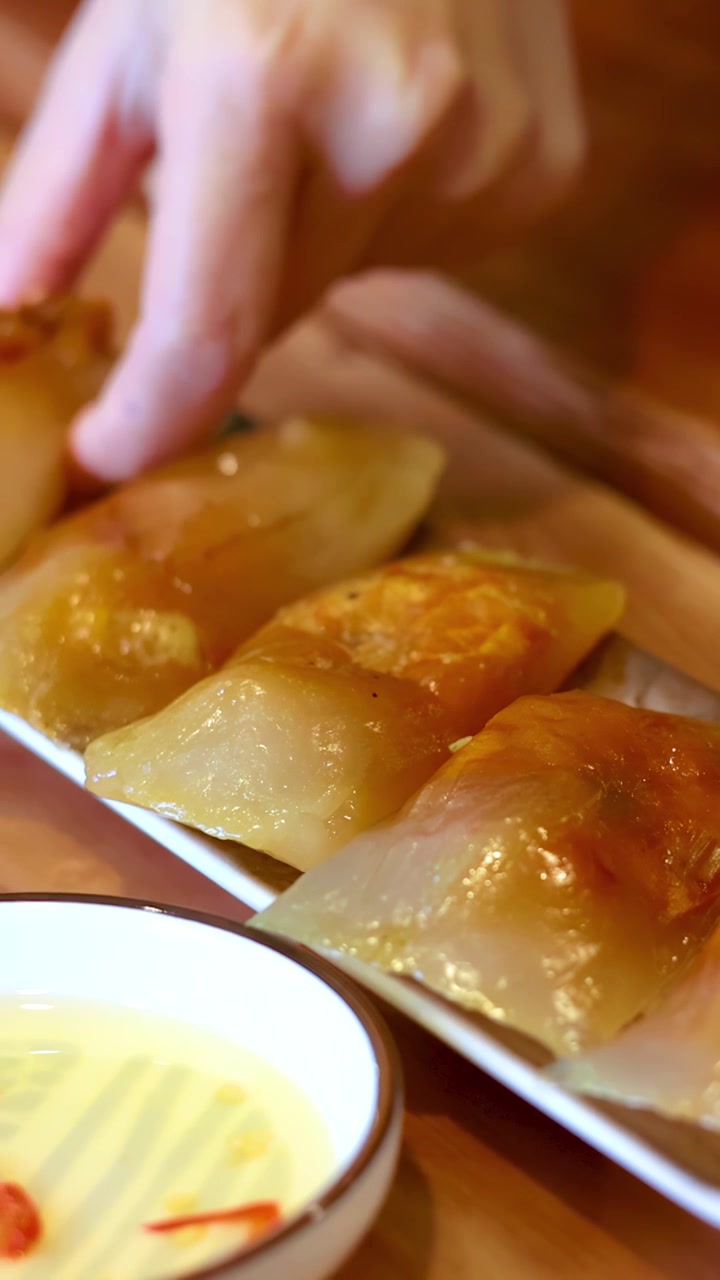 Close-up shot of a hand picking up translucent tapioca dumplings from a wooden table