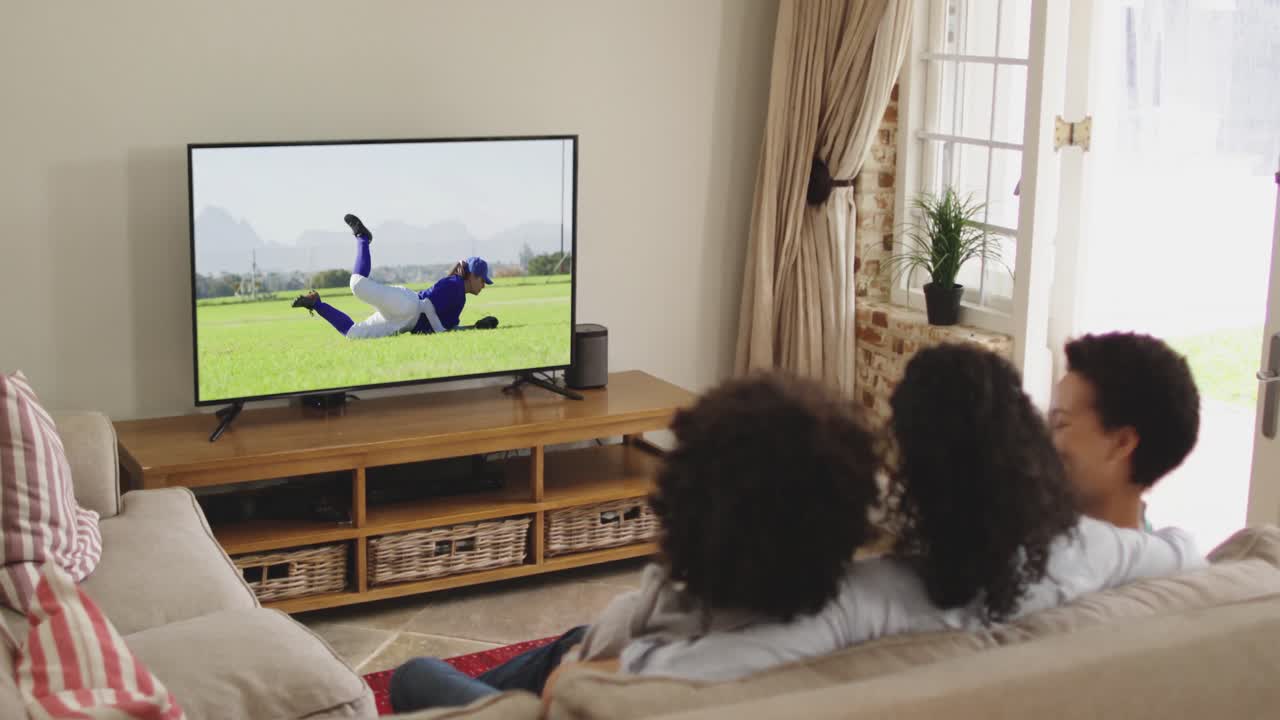 Famiglia felice seduta a casa insieme che guarda una partita di baseball in TV