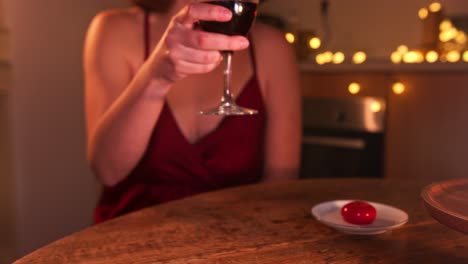 mujer sentada en la mesa con un vestido rojo sexy tomando un vaso de vino. fiesta de navidad. estática