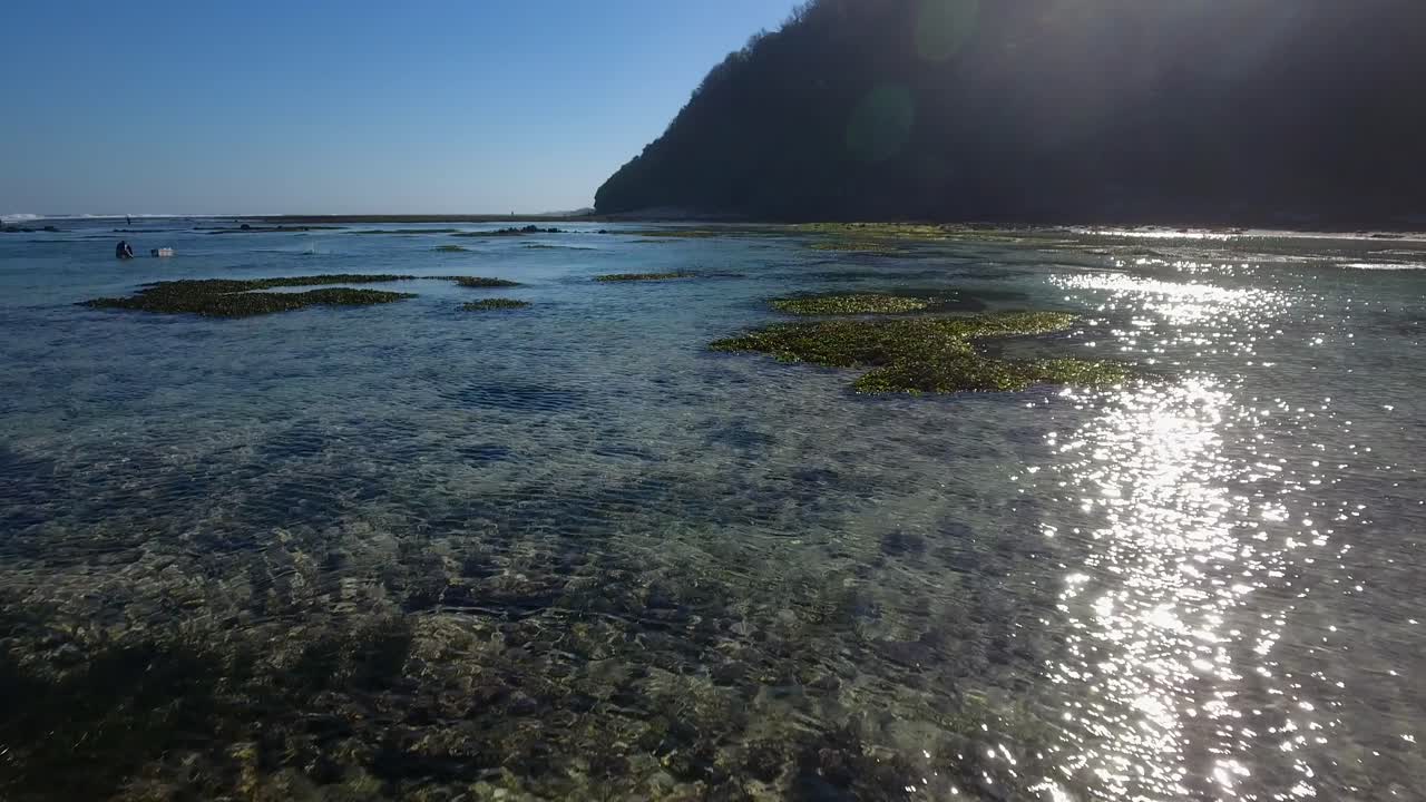 volando bajo sobre los arrecifes de coral de bali indonesia, siluetas de pescadores trabajando en el arrecife para pescar