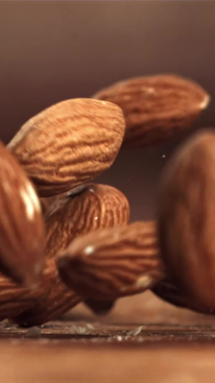 Des amandes tombant au ralenti sur une surface en bois.