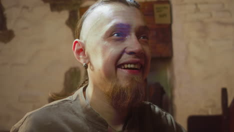 bearded man with wide smile in tavern closeup. excited guy see wanted item in medieval store. foolish pub guest looks forward after several shots