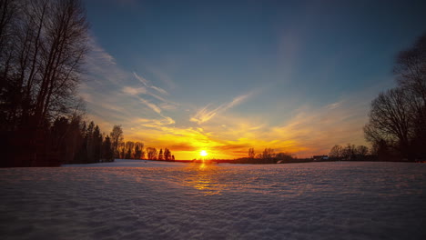 snowy, winter landscape timelapse and the orange sun on the horizon, with the clouds advancing