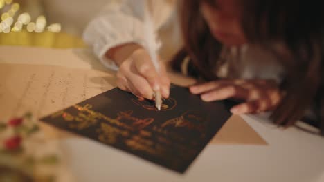 girl writing a christmas letter with gold calligraphy