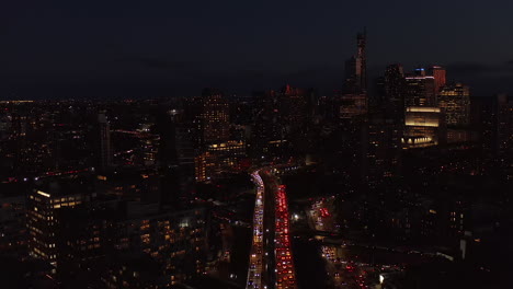 Aerial-view-of-heavy-traffic-in-streets-of-night-town.-High-rise-building-with-lighted-windows.-Brooklyn,-New-York-City,-USA