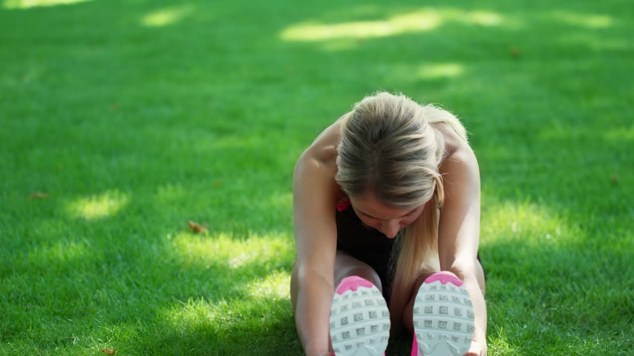 Athlete woman doing stretch exercise before fitness training in summer park