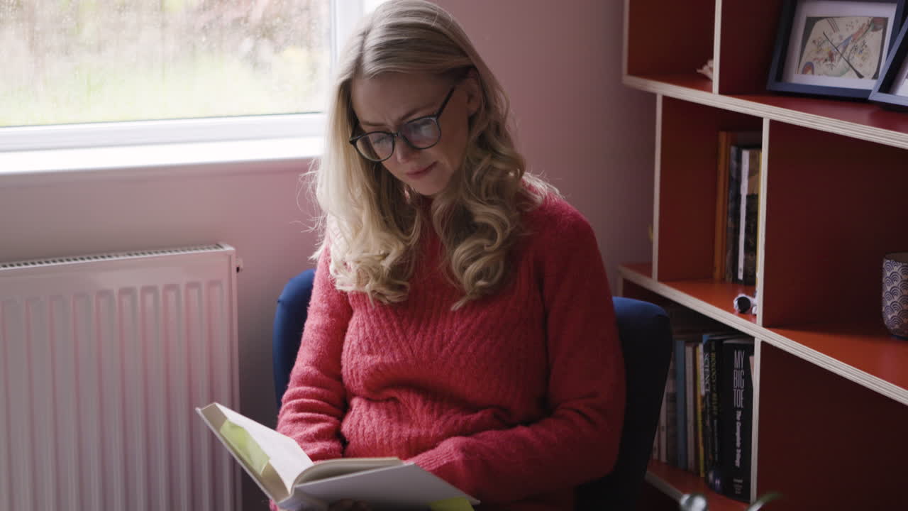 mujer leyendo un libro junto a la ventana