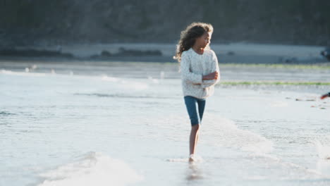 boy and girl playing and jumping over waves on autumn beach vacation