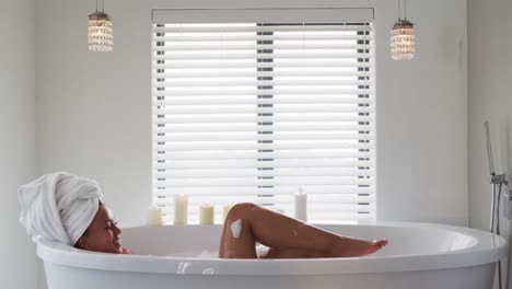 african american woman blowing soap bubbles in the bath tub in the bathroom at home