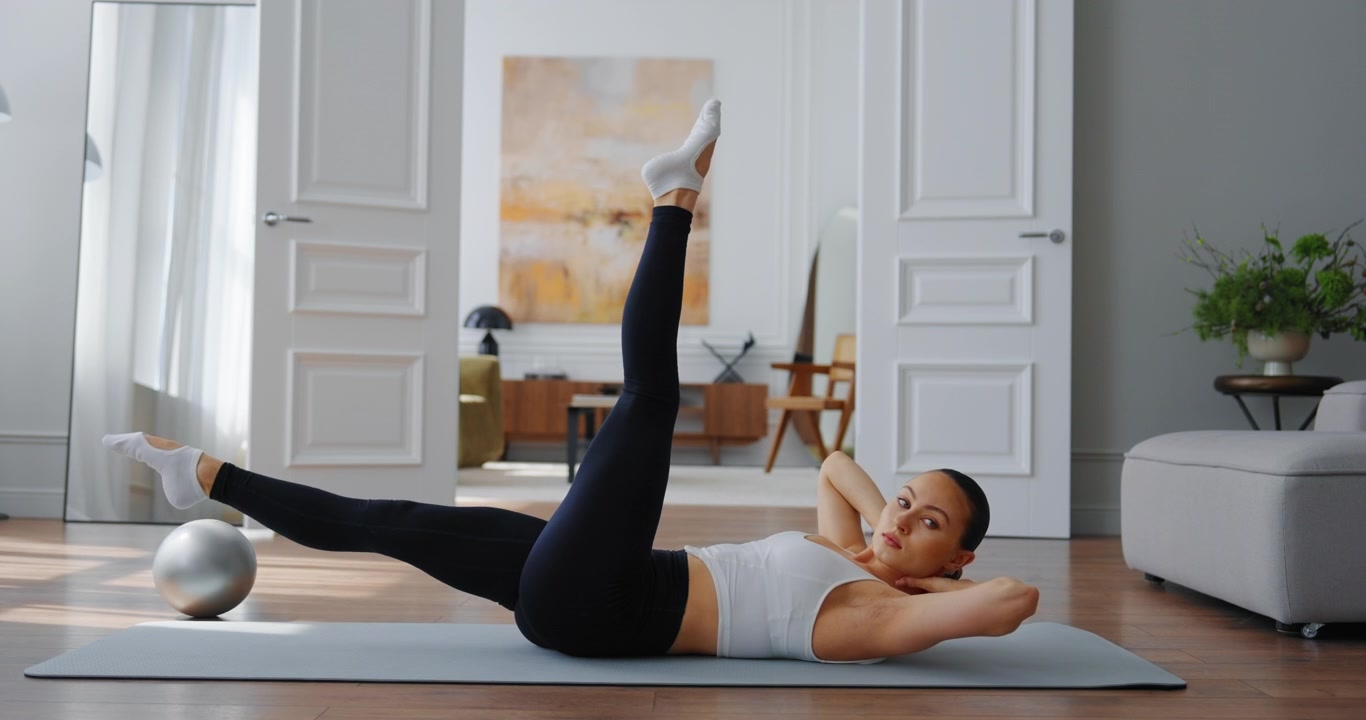 Young Woman Exercising Core Muscles with Leg Raises on Yoga Mat