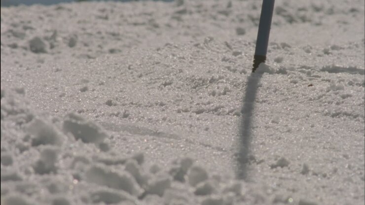 A skier races down a slope past a slalom pole
