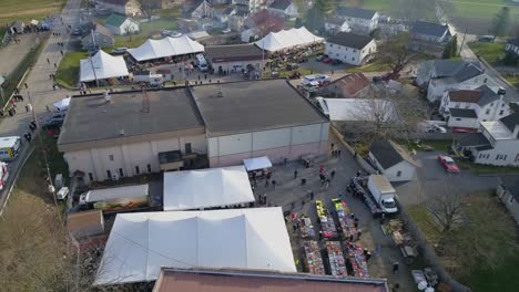 aerial of an early morning view of opening day at an amish mud sale selling farm equipment to quilts