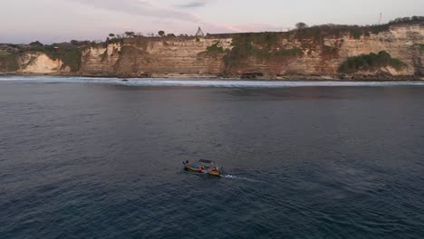 Touristen-In-Motorisierten-Traditionellen-Balinesischen-Jukung-Booten,-Die-In-Der-Nähe-Der-Klippen-Segeln