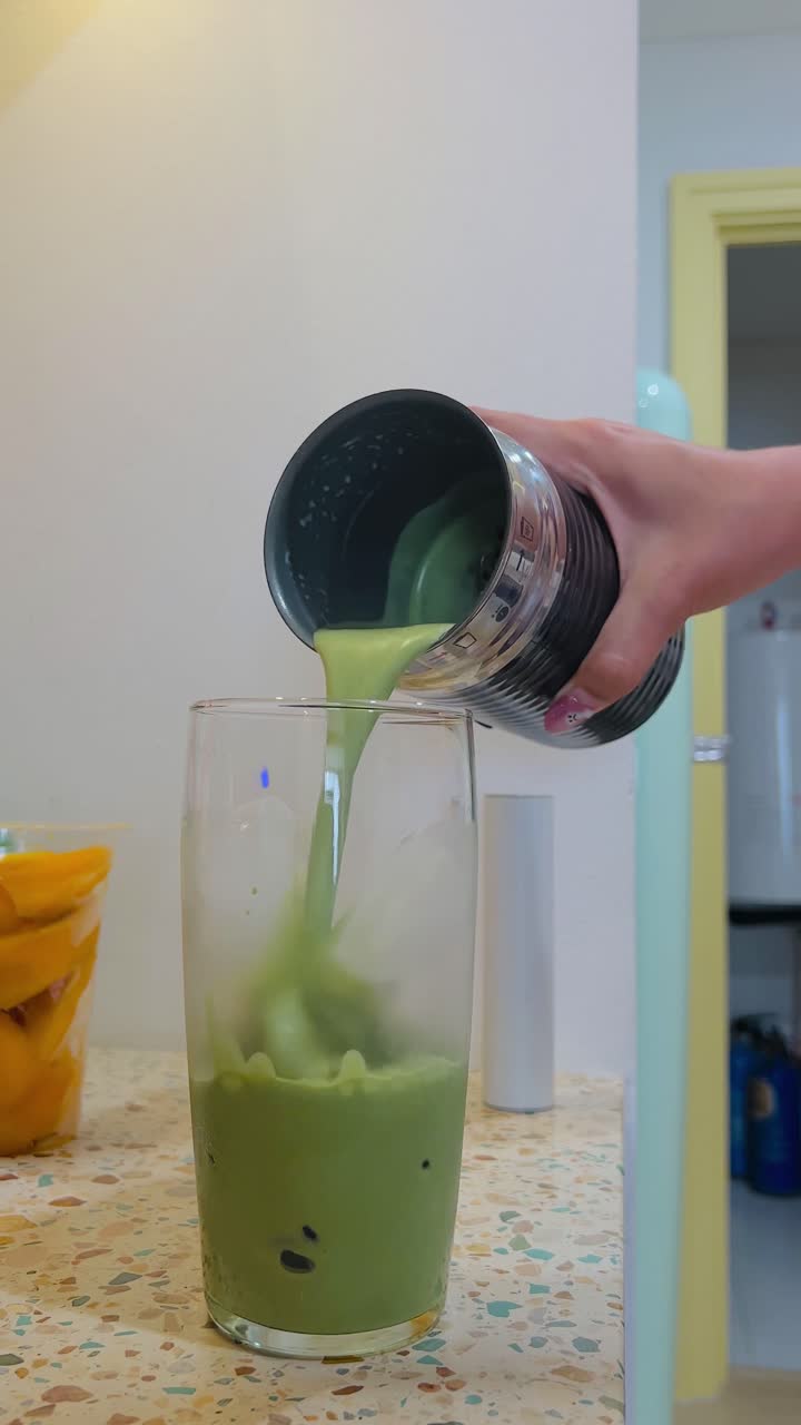 Preparazione di un Iced Matcha Latte versato da un montalatte