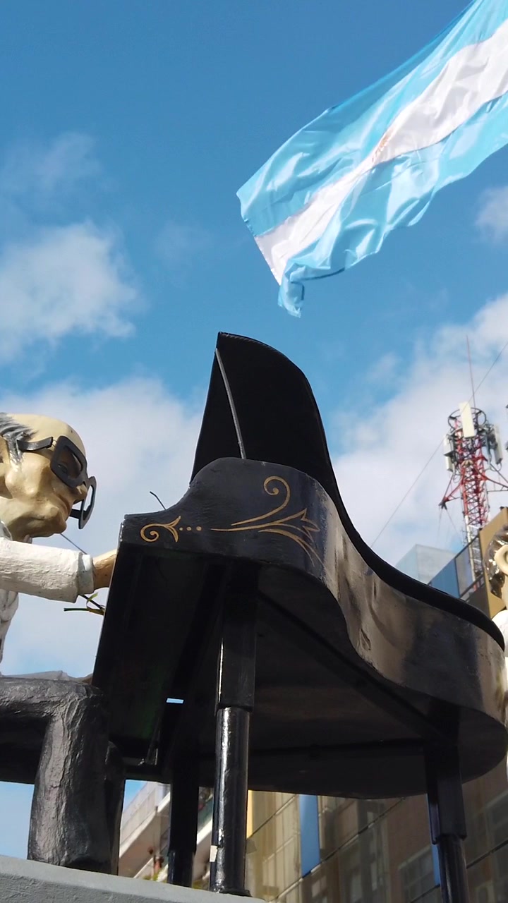 Vue verticale du monument à Osvaldo Pugliese, célèbre pianiste de Buenos Aires, avec le drapeau argentin en arrière-plan.