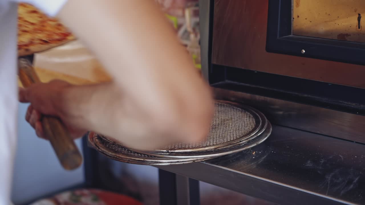 Pizza is ready. Pizzeria master making pizza. Chef pulling pizza out of the oven using the pizza spatula. Cook puts the finished pizza on the plate. Tasty pizza.