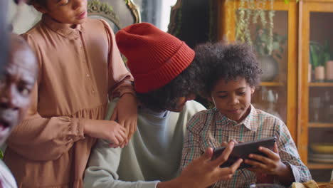 kids playing on tablet at home dinner