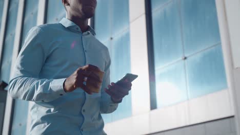 businessman using smartphone while walking outside a modern building