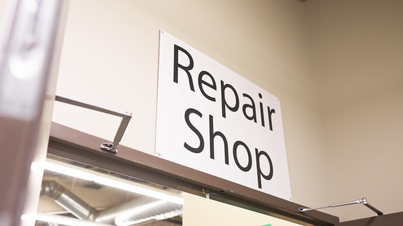 Gimbal shot shows white REPAIR SHOP sign over the workshop’s double doors