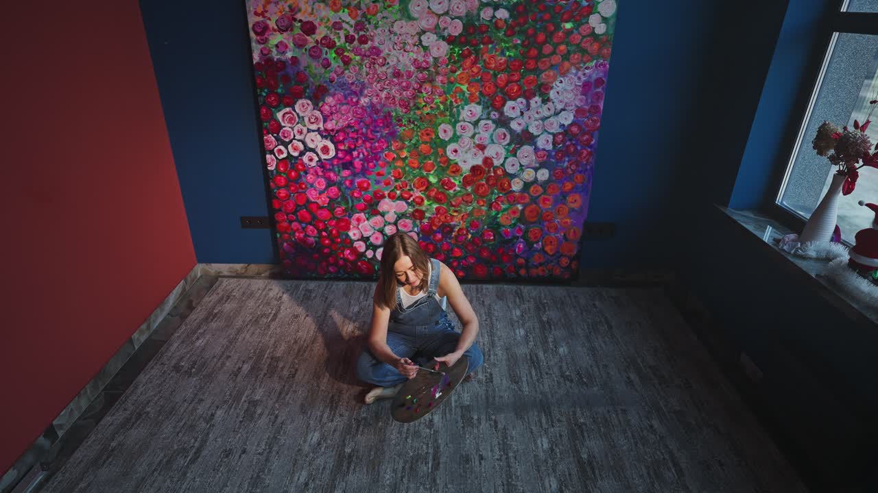 Donna creativa che mescola colori su una tavolozza in uno studio d'arte