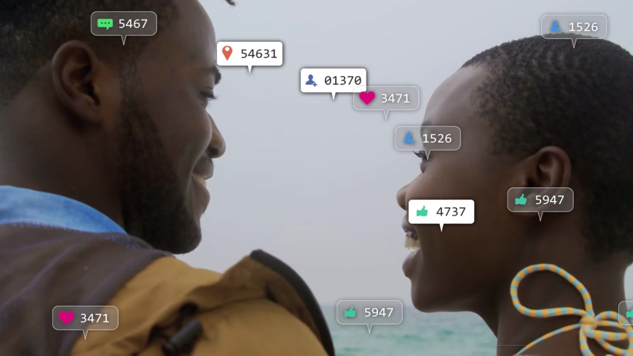 Couple facing shore as social media notifications rising, heart and like bubbles around, smiling