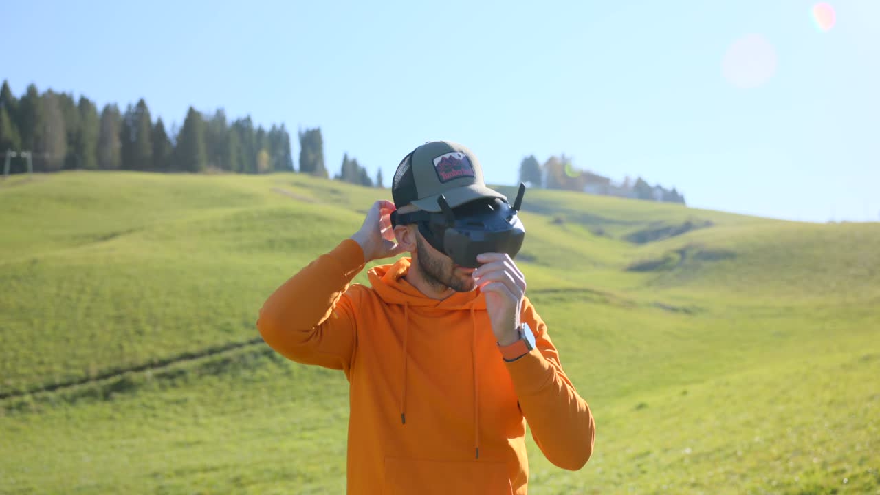 Man puts on VR goggles outdoors with scenic green hills in background