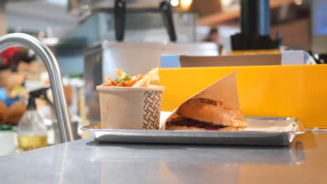 beef burger and french fries in a takeaway paper box on table