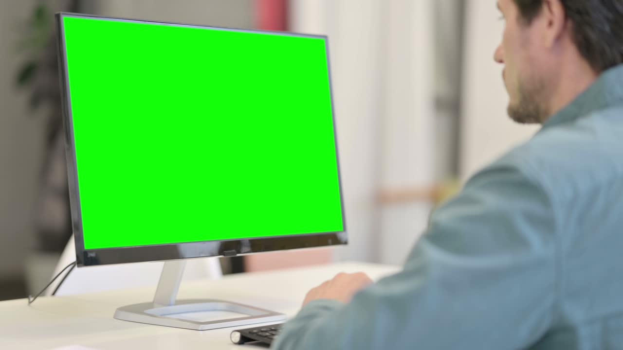 hombre usando el escritorio con pantalla clave de croma verde