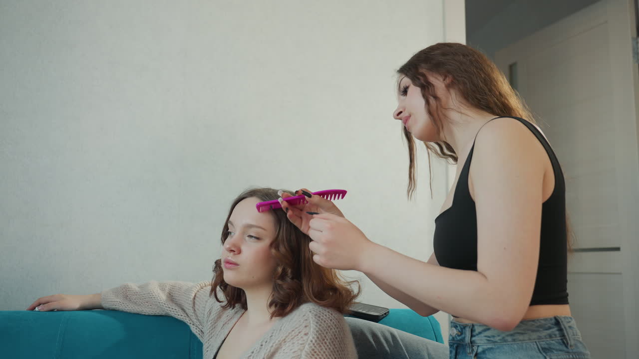 Friend Gently Interacting With Woman On Sofa, Comfortable Domestic Scene With Playful Grooming And Friendly Chat, Friendly Individual Styling Seated Woman In Cozy Living Room Setting