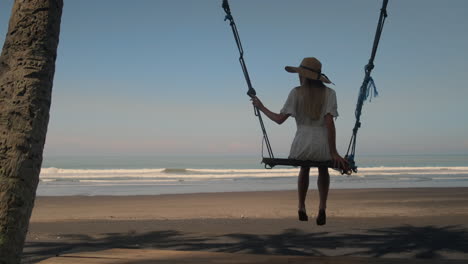 woman swinging on beach at sunset
