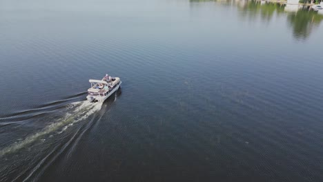 pontoon boat sailing and leaving wake across the lake