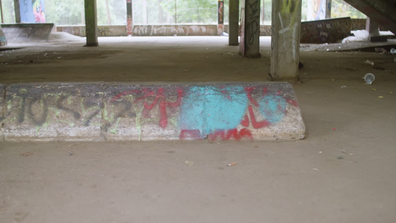 Boy's feet on skateboard in a ruined building.