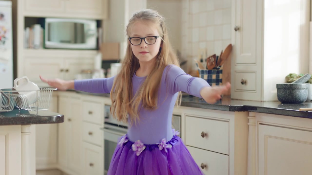Young Girl Dancing in a Kitchen Wearing a Purple Tutu