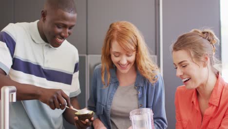 Happy-group-of-diverse-friends-preparing-healthy-drink-in-kitchen-together