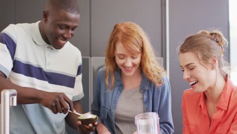un grupo feliz de amigos diversos preparando una bebida saludable en la cocina juntos