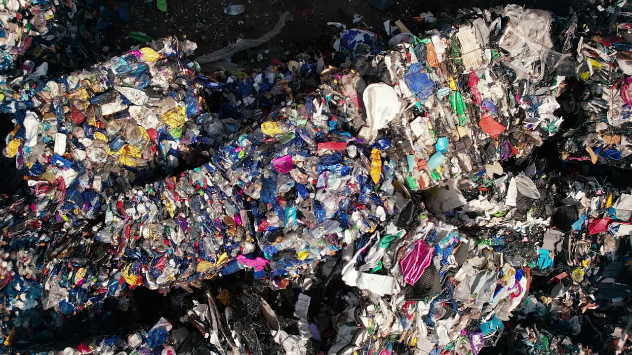 Multiple cubes of compressed multicoloured plastic garbage at waste recycling factory in open air