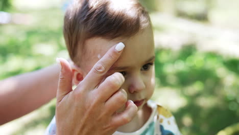 mother applying sunscreen to baby's face
