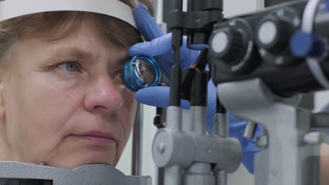 woman doctor is viewing through ophthalmoscope in eyes of patient in ophthalmologic clinic. professional inspection of vision