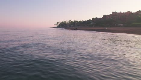 Static-shot-over-the-sea-during-sunset-on-a-secluded-beach-in-Marbella,-Spain