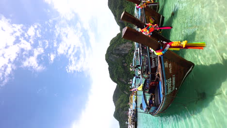 vertical view of traditional longtail boats floating in the clear water in koh phi phi island, thailand