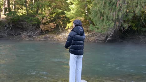 lone person catching fish with fishing rod in the river flowing through the forest