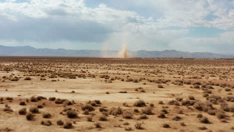 a sudden sandstorm or dust devil shoots sand high into the sky as seen from an aerial approach