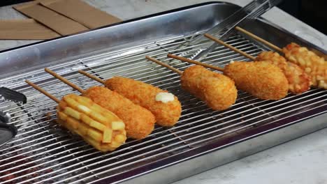 close up shot of corn dog fried food being sold in a window during car free day, carnival or fair